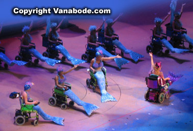 Image of Bette Midler as her famous character, Delores Delago multiplied 20 times by her cast of wheelchair mermaids.